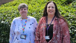 Susan Oldfield and Debbie Ashton, Alliance Homes' Money Advisors standing in front of a bush.