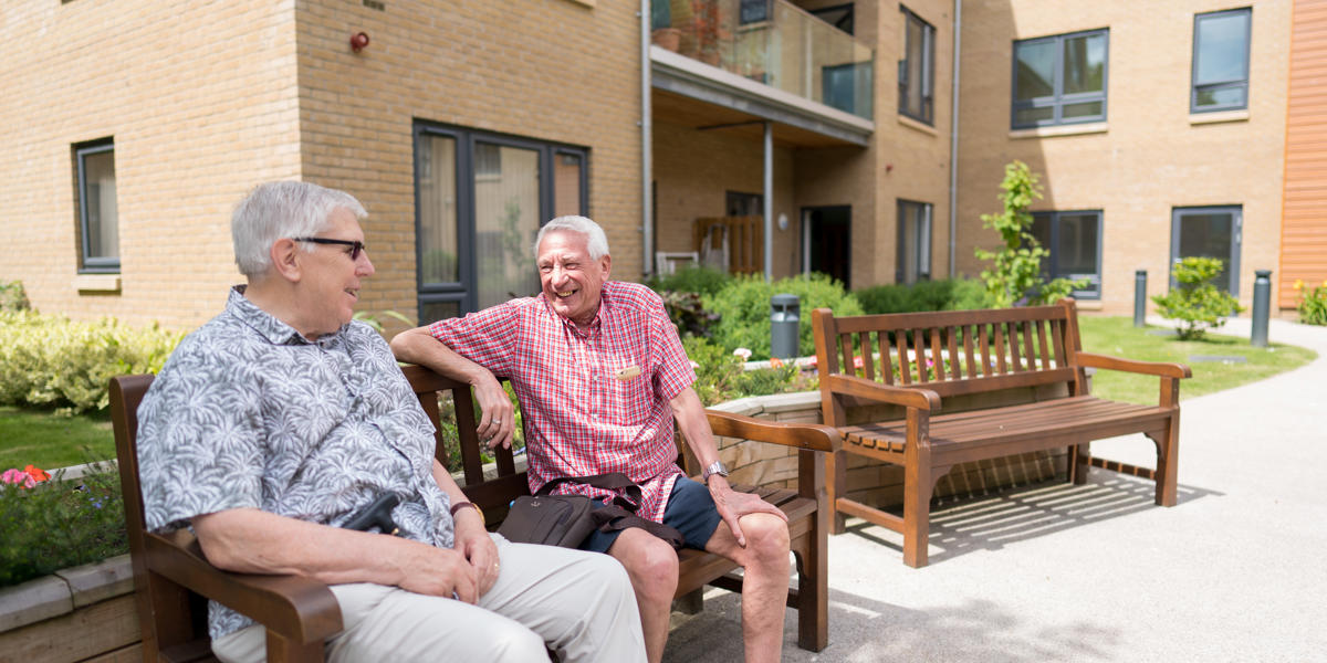 two men sat on bench outside their homes