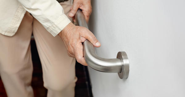 senior person holing onto wall mounted mobility aid