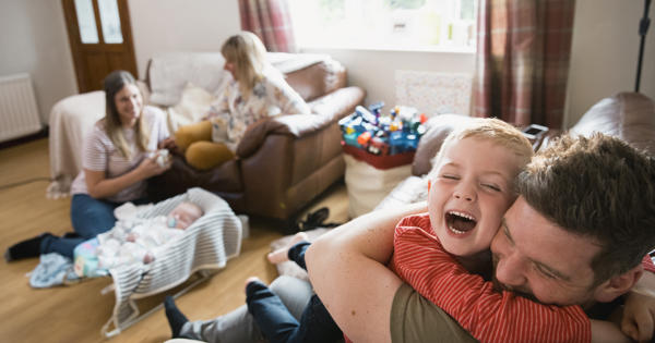 Father and child cuddle on the sofa as two women sit on the floor further away