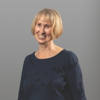 Gill, Customer Feedback Panel member, wearing a blue jumper against a grey background.