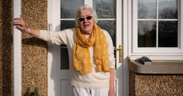 Lady Wearing A Scarf Standing By Her Front Door