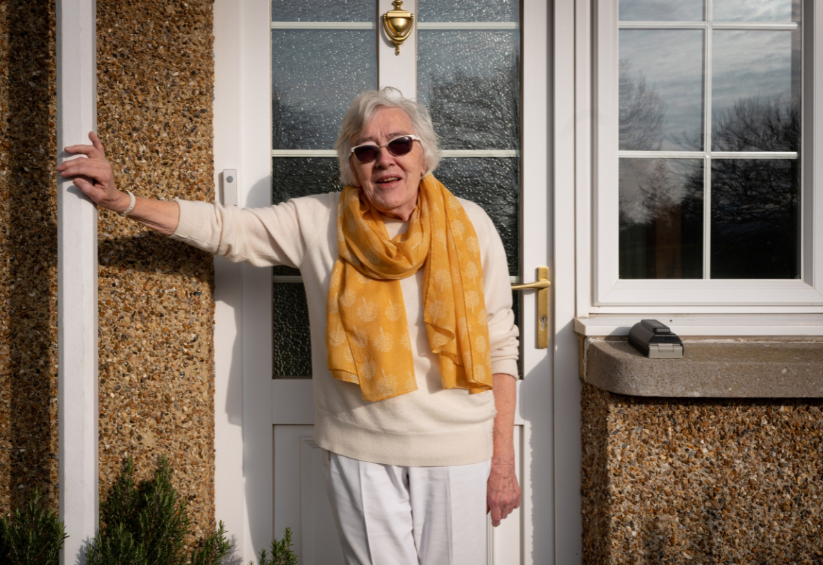 Lady Wearing A Scarf Standing By Her Front Door