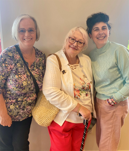 Customer Feedback Panel members, Mary, Angela and Alisa, standing against a beige wall. All three women are middle-aged, wearing brightly coloured and patterned outfits.