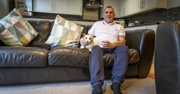 Man at home with dog on sofa